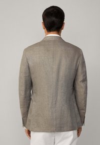 Blazer gris clair en tissu texturé, avec une fente simple à l'arrière, des revers crantés et des poignets boutonnés.
