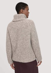 Hellgrauer gestrickter Pullover mit hohem Kragen, sichtbarer Rippstruktur und leicht oversized Passform. Weiches Material mit einem gemütlichen Aussehen.