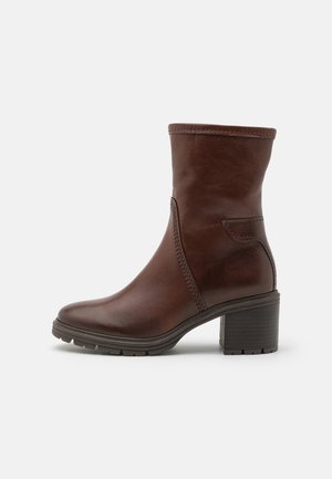 Brown leather ankle boot with a smooth finish, rounded toe, side stitching detail, and a chunky heel for stability. Rubber sole for traction.