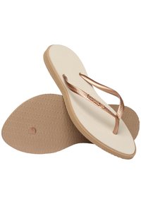 Flip-flops with a textured white footbed and brown rubber sole. Features bronze straps with a woven pattern and logo detail.