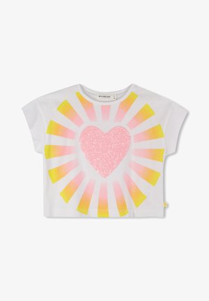 Kortmouwige witte crop top met een grote roze hart van pailletten, omringd door een zonnestraalpatroon in roze en geel.