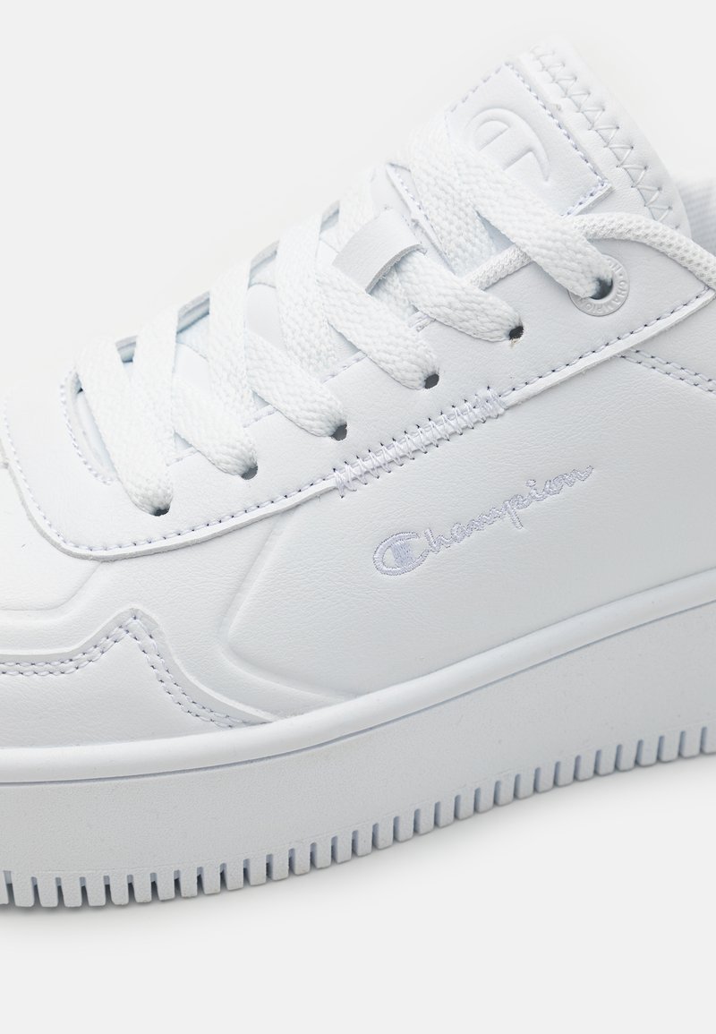 Sneaker bianche realizzate in pelle sintetica, con lacci piatti, punta rotonda e dettaglio logo impresso sul lato. Suola testurizzata.
