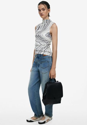 White sleeveless top with black wave pattern, blue loose jeans, and a black backpack. Footwear features a white base with black accents.
