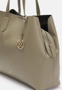 Grön läder tote-väska med en strukturerad form, prydd med en guldfärgad charm, dragkedjefack och slät textur.