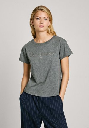 Camiseta de algodón gris con cuello redondo, mangas cortas y un logo impreso en plata. La tela parece suave y tiene un ajuste casual.