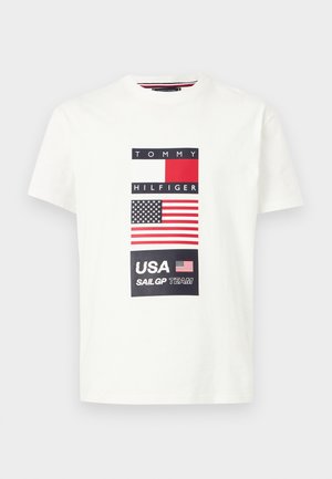 Biała koszulka z krótkim rękawem z nadrukiem flag Tommy Hilfiger i USA oraz napisem "USA SailGP TEAM" na środku przodu.