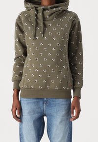 Sweat à capuche vert olive avec un col bénitier, présentant un motif floral géométrique en blanc, vert et marron. Fini avec des poignets et un ourlet côtelés.
