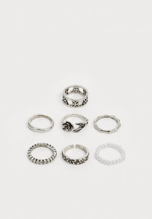 Seven silver rings in varied designs: detailed floral and leaf accents, smooth bands, beaded texture, and one with small pearls.