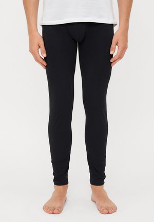 Collants noirs en matériau extensible et lisse. Design près du corps avec une taille haute, sans motifs visibles ni matériel.