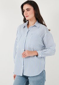Hemd mit blauen und weißen vertikalen Streifen, langen Ärmeln, klassischem Kragen und zwei Brusttaschen, aus leichtem Stoff.