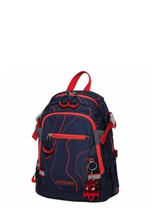Sac à dos bleu marine avec des accents rouges, présentant une surface texturée, plusieurs compartiments et un porte-clés décoratif en sequins.