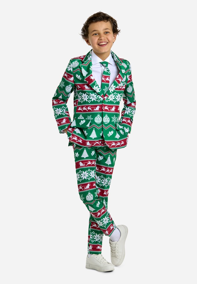 Completo natalizio verde con fiocchi di neve bianchi, renne, alberi e decorazioni, abbinato a una camicia bianca e una cravatta verde, completato con sneakers.