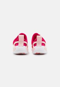 Rosa och vit sneaker med ett mjukt textilövre, en dämpad rosa inredning och en vit sula med röda detaljer. Inkluderar en bakre dragögla.