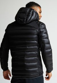 Čierna péřová bunda s kapucňou, ktorá má horizontálne prešívanie a hladký, lesklý povrch. Dizajn má priliehajúce rukávy a bočné akcenty.