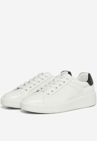 Sneaker bianche in pelle dal design elegante, con accenti neri sul tallone, lacci piatti e suola in gomma texturizzata.