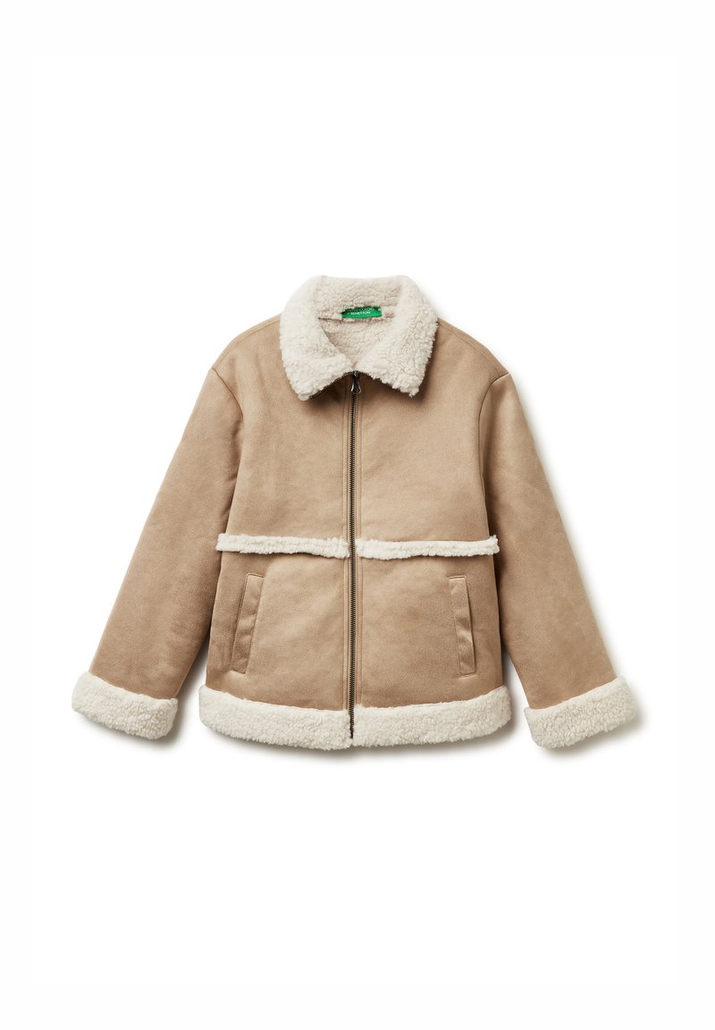 Giacca shearling color sabbia con chiusura a zip, colletto e polsini morbidi bianchi, con due tasche laterali e una cucitura orizzontale foderata in pelliccia.