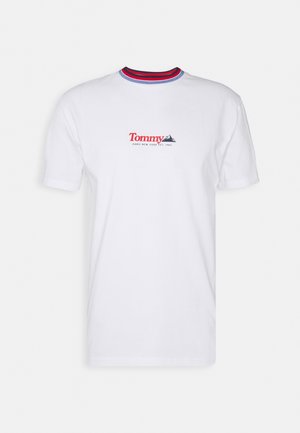Camiseta de algodón blanca con mangas cortas, que presenta un cuello redondo con acentos de canalé en rojo y azul y una impresión de logo en rojo y azul.