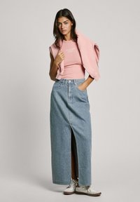 Roze aansluitend topje gecombineerd met een lichtblauwe denim maxi rok met een voorkant split, gedragen met witte sneakers voor een casual look.