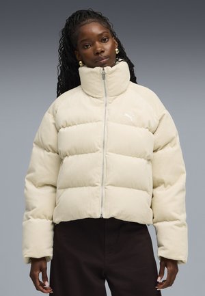 Beige corduroy pufferjack met hoge kraag en voorritssluiting. Bevat gewatteerde secties en een klein logo aan de linkerkant.