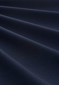Námořnická modrá látka s hladkým povrchem, vykazující jemné faldy a decentní lesk. Materiál vypadá lehce a pružně.