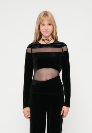 Haut noir à manches longues avec des panneaux en velours et en maille transparente, doté d'un design asymétrique et de textures lisses.