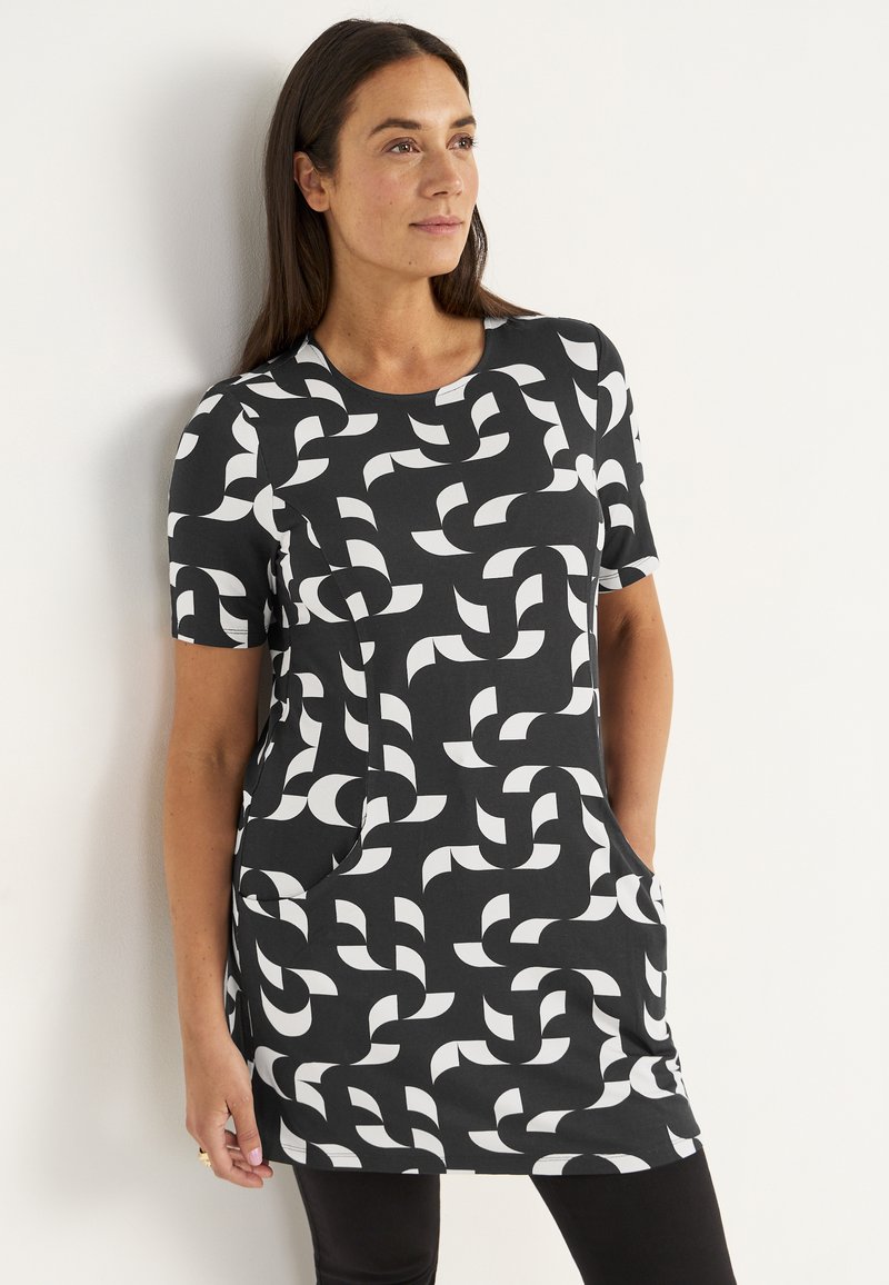 Korte mouwen tuniek in zwarte stof met een wit geometrisch patroon, ronde halslijn en zijzakken. Zachte textuur, casual pasvorm.