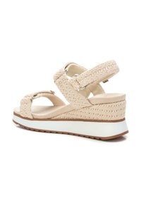 Sandalo con zeppa beige caratterizzato da cinturini in tessuto intrecciato, fibbia regolabile e un tacco testurizzato con una suola intermedia bianca e una suola esterna in gomma marrone.