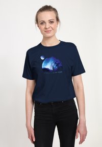 T-shirt in cotone blu navy con una grafica che mostra una silhouette su uno sfondo cosmico colorato, con la scritta "UN MONDO COME NESSUN ALTRO" sotto.