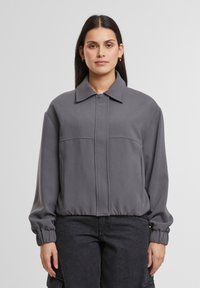 Gray cropped jacket with a collar, featuring a zip closure, ribbed cuffs, and dividing seams. Soft fabric with a smooth texture.