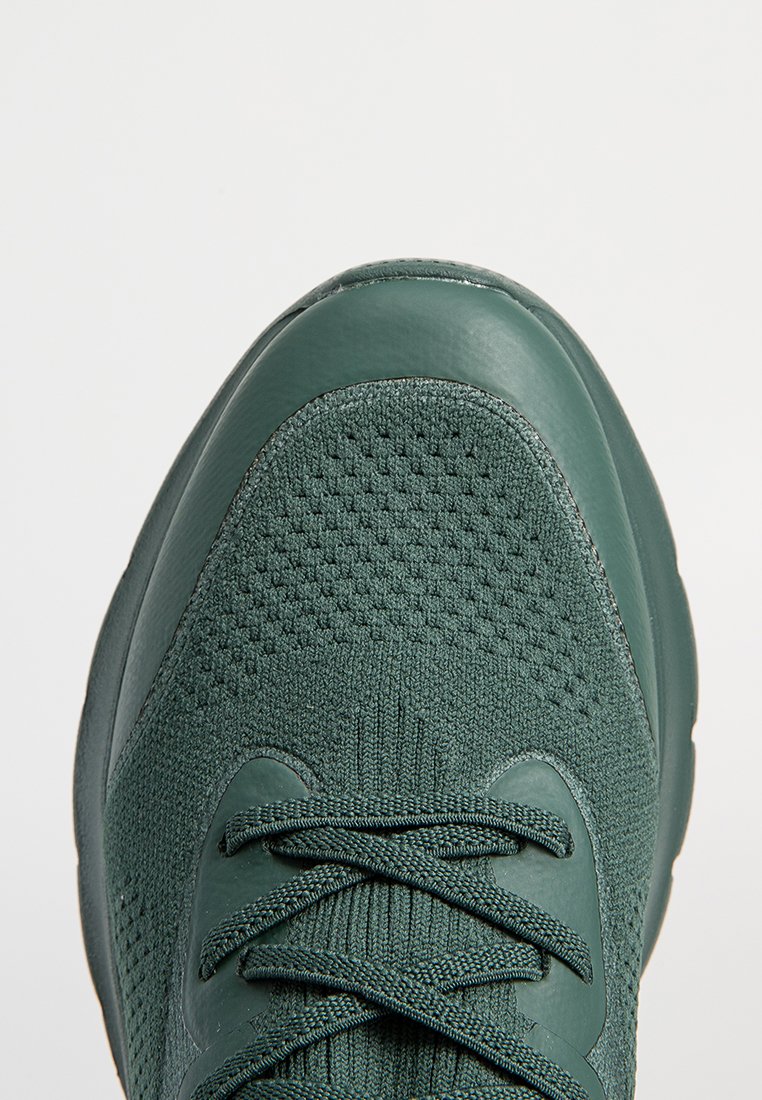 Grüner Sportschuh mit einem strukturierten Mesh-Obermaterial, glatten Lederakzenten und Schnürung an der Vorderseite. Formschön für Komfort mit einer abgerundeten Zehenpartie.