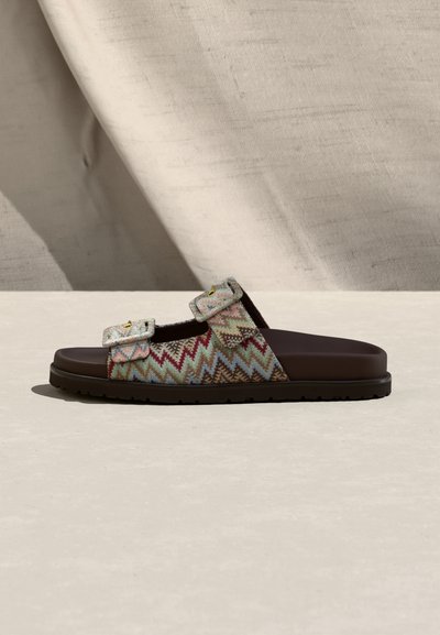 Sandale à bouts ouverts avec deux brides en tissu à motifs en zigzag ajustables dans des couleurs pastel douces et une semelle marron foncé.