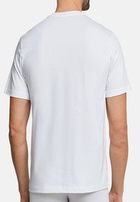 T-shirt blanc à manches courtes en coton doux, doté d'un col classique et d'un design épuré et minimal sans logos ni motifs.