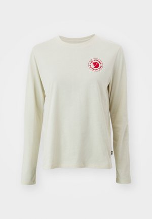 Lange mouwen lichtbeige T-shirt van katoen, met een ronde hals en een rood cirkelvormig logo op de borst met tekst en een afbeelding.