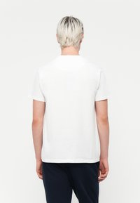 White short-sleeve t-shirt with a round neckline, made of smooth fabric. Back view shows simple design, no visible patterns or accents.