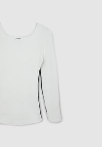 Top bianco a maniche lunghe con scollatura quadrata e accenti neri sui lati. Presenta una silhouette aderente e un tessuto testurizzato.