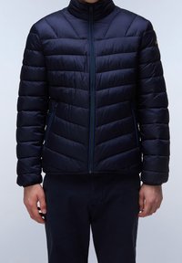 Giacca a vento imbottita di un blu navy scuro, con un design trapuntato, colletto alto e chiusura frontale con zip. Materiale leggero e testurizzato con tasche laterali.