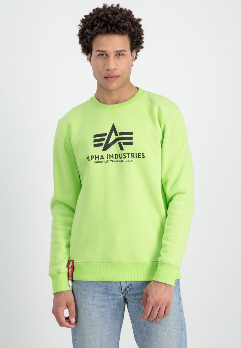 Sudadera verde neón con puños y dobladillo acanalados, que presenta una impresión de logotipo negra y una etiqueta roja en la costura inferior izquierda. Diseño casual, unisex.