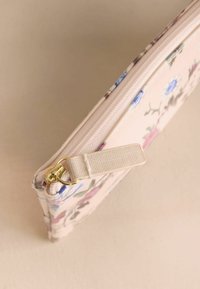 Gėlėta užsegama maišelė, pagaminta iš blizgaus medžiagos. Turi švelnią rožinę fono spalvą, mėlynas ir rožines gėles bei auksinės spalvos furnitūrą.