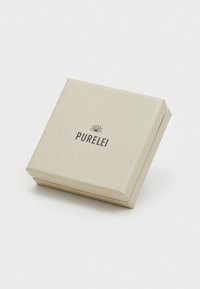Mala bež kutija za nakit s suptilnim reljefnim uzorcima lista i logotipom "PURELEI" otisnutim crnom bojom na poklopcu.