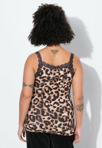 Camisola con stampa leopardata caratterizzata da una consistenza morbida e liscia, bordo in pizzo nero e spalline regolabili, mostrata da dietro su uno sfondo neutro.