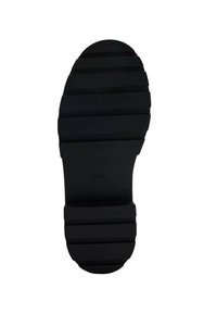 Suela de zapato de goma negra con canales horizontales y punta redonda. Tacón plano y superficie texturizada para mayor tracción.