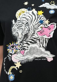 Zwart T-shirt met een grote witte tijgerafbeelding, omringd door kleurrijke geborduurde sterren, wolken en een vlinder met roze en blauwe accenten.