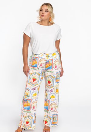 Witte top met korte mouwen gecombineerd met kleurrijke, gemusterde wijde broek met fruit en locaties, waaronder "Hawaii" en "Los Angeles."