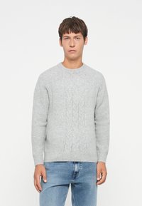 Light gray knitted sweater with a cable pattern, round neckline, and long sleeves paired with blue jeans. Soft, textured fabric.