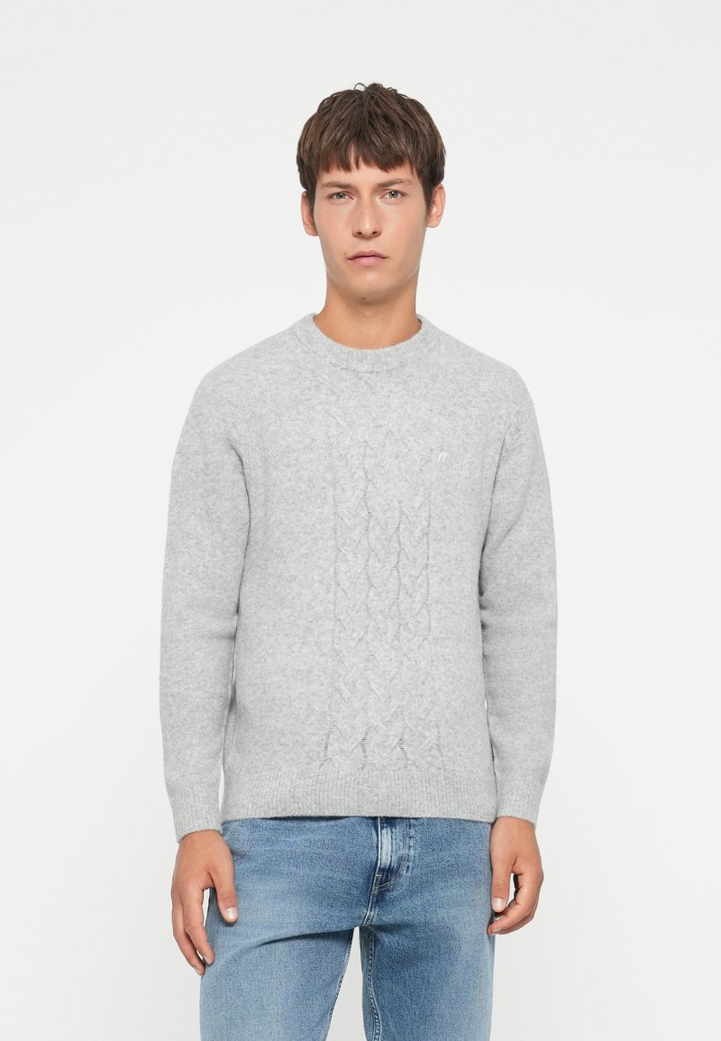 Light gray knitted sweater with a cable pattern, round neckline, and long sleeves paired with blue jeans. Soft, textured fabric.