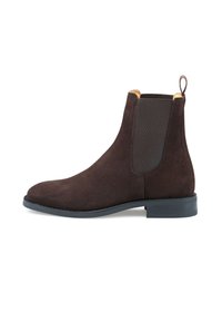 Bottines Chelsea en suède marron avec des panneaux élastiques sur les côtés, bout pointu et une languette à l'arrière. Semelle en caoutchouc noir avec un relief modéré.