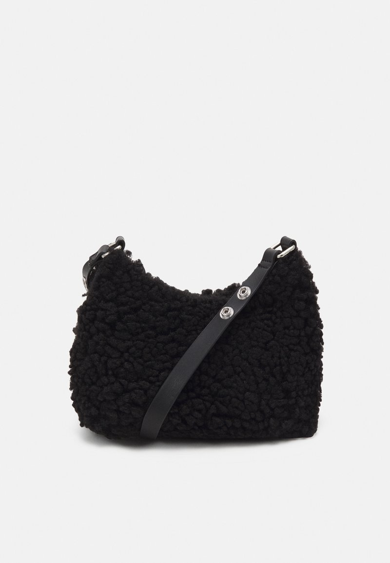 Sort tekstureret fleece skuldertaske med justerbar læderrem og sølvfarvet hardware på ensfarvet baggrund.