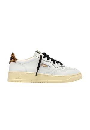 Zapatilla blanca de corte bajo con cordones negros, suela beige y detalle de estampado de leopardo en la lengüeta del talón.