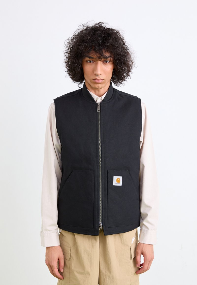 Schwarze ärmellose Weste mit Reißverschluss, zwei Vordertaschen und Logo-Patch. Hergestellt aus strapazierfähigem Material und einem klaren, minimalistischen Design.