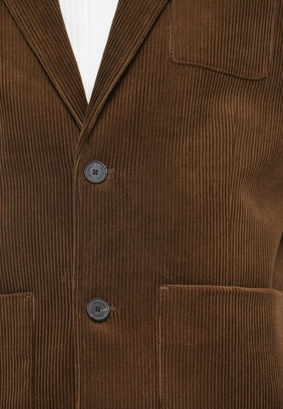 Brun fløjlsblazer med lodret ribbing, to knapper og en lomme. Glat tekstur med en klassisk pasform.